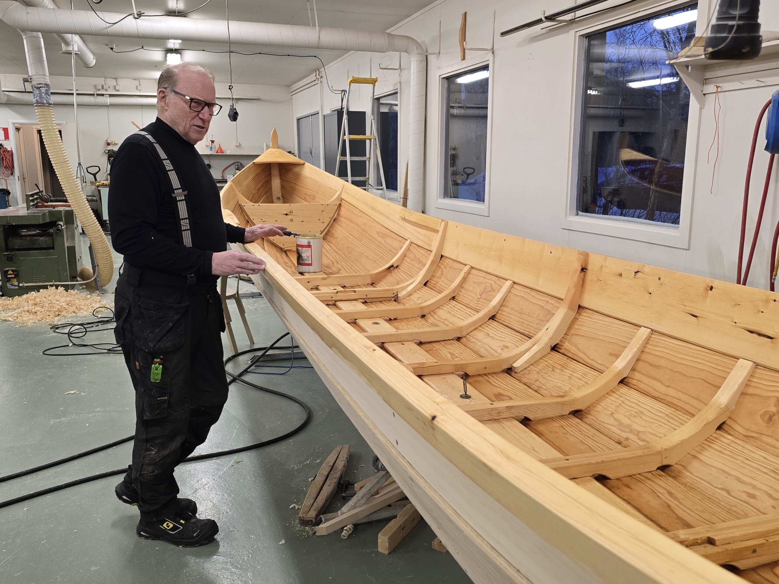 veneenrakentaja uuden puuveneen vieressä