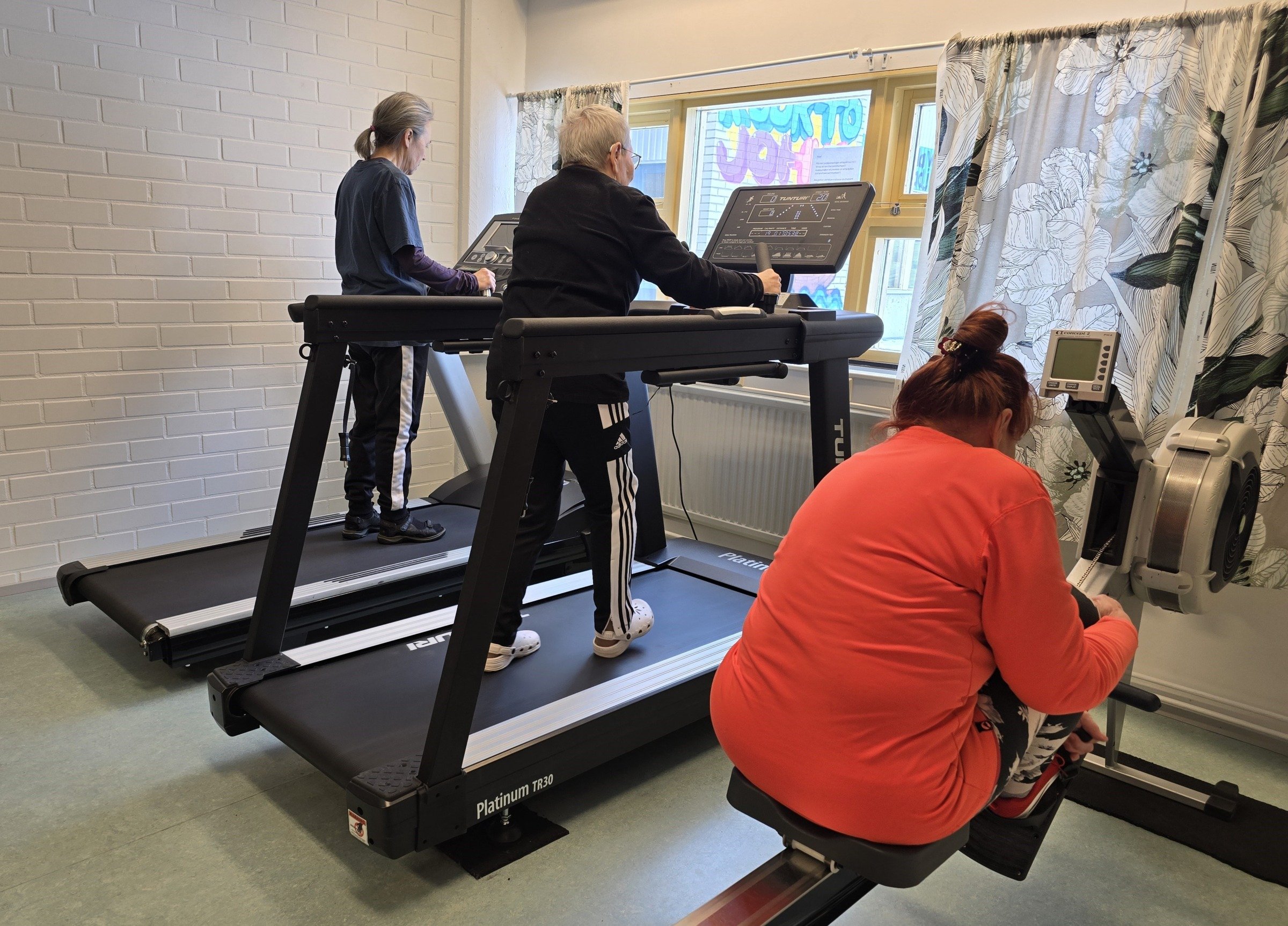 ihmisiä kuntosalilaitteilla