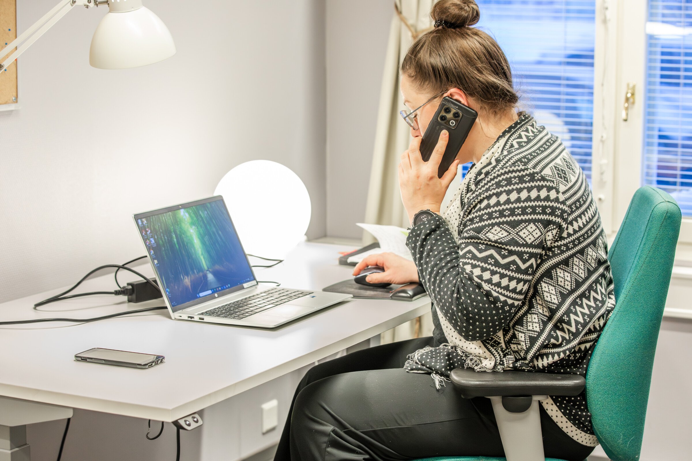 nainen istuu työpöydän ääressä